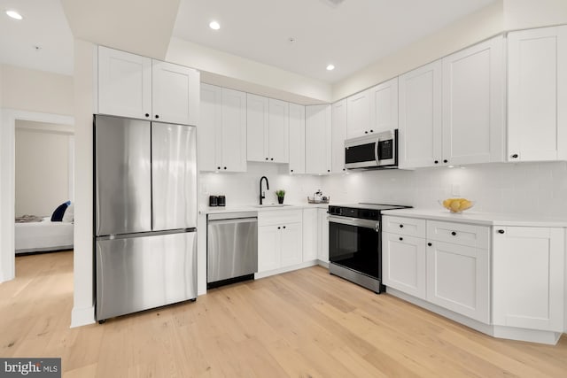 kitchen featuring appliances with stainless steel finishes, white cabinets, and light hardwood / wood-style floors