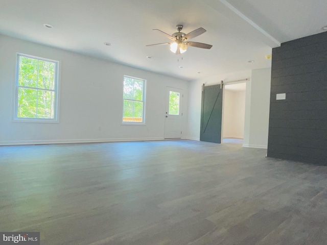 spare room featuring beamed ceiling, ceiling fan, a healthy amount of sunlight, and a barn door