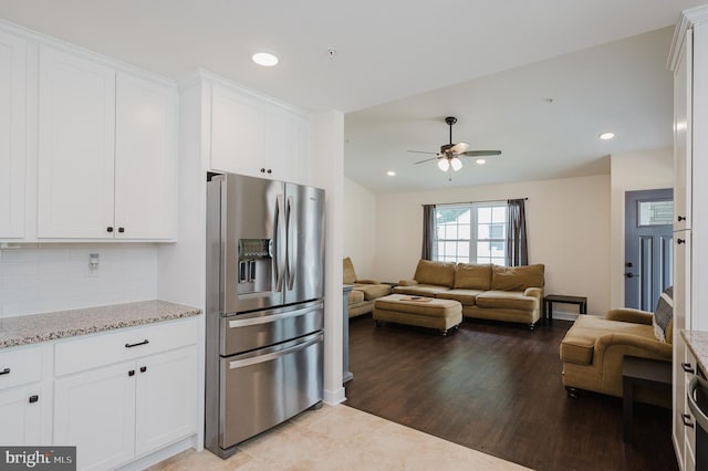 kitchen featuring tasteful backsplash, stainless steel refrigerator with ice dispenser, white cabinets, and light stone counters