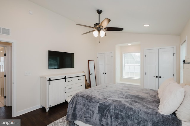 bedroom with visible vents, baseboards, multiple closets, vaulted ceiling, and dark wood-style flooring