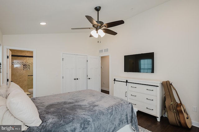 bedroom with vaulted ceiling, connected bathroom, ceiling fan, dark wood-type flooring, and a closet