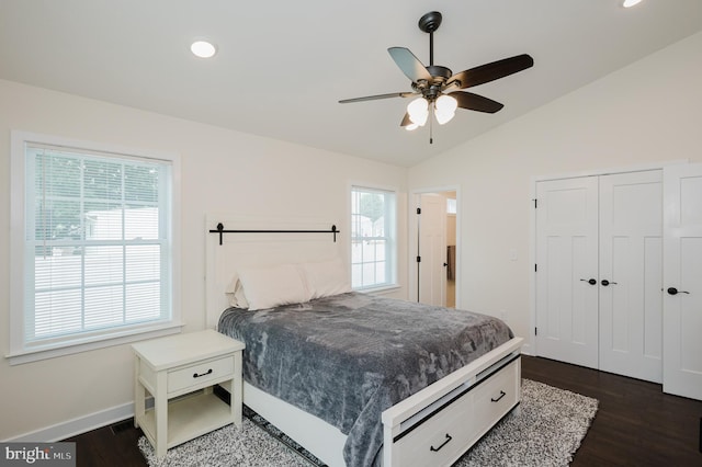 bedroom featuring multiple windows, lofted ceiling, baseboards, and dark wood-style floors