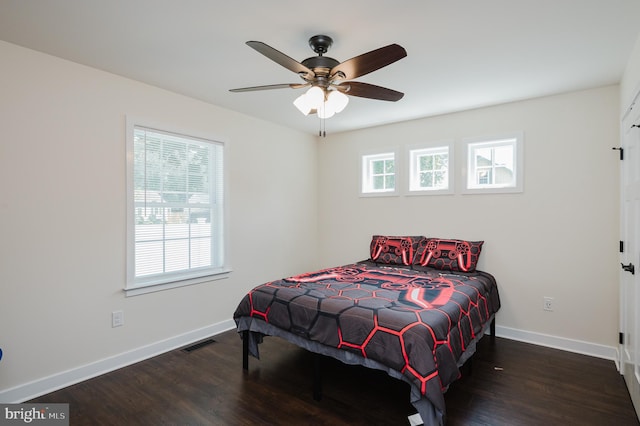 bedroom with a ceiling fan, wood finished floors, visible vents, and baseboards