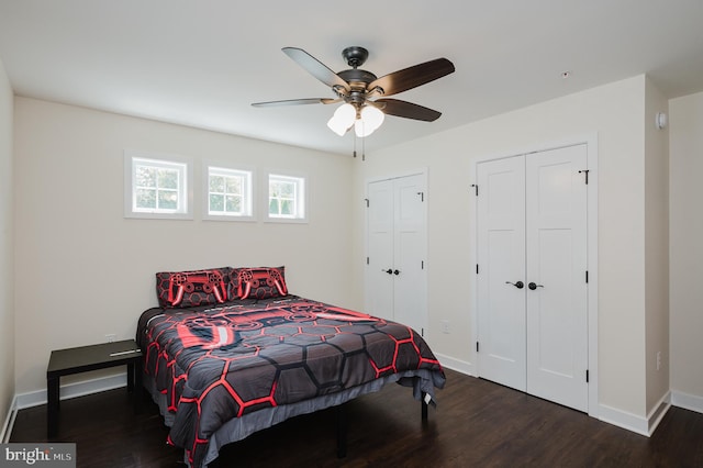 bedroom featuring a ceiling fan, wood finished floors, baseboards, and two closets