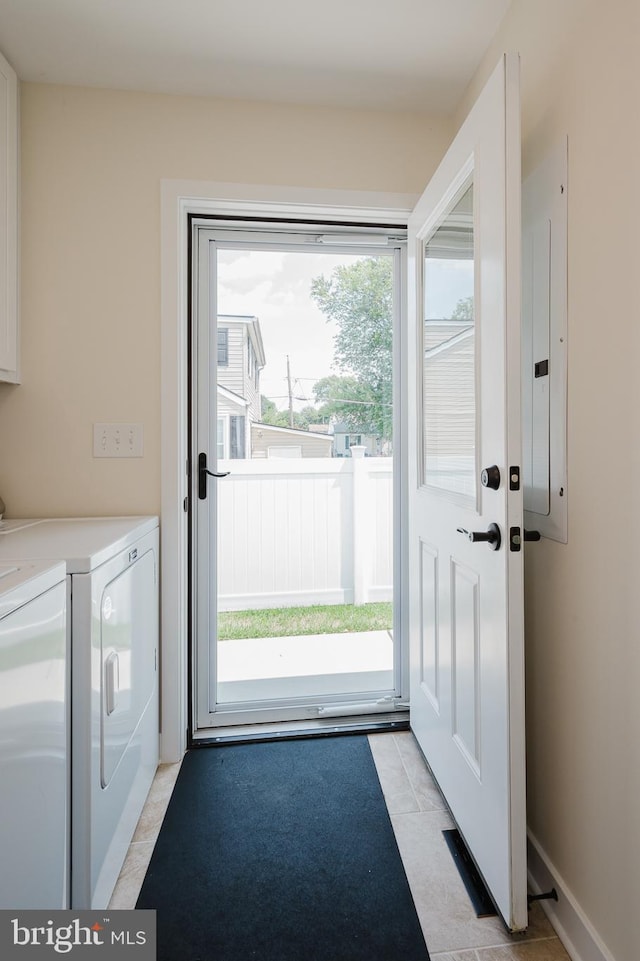 doorway to outside featuring washer and dryer, light tile patterned floors, and electric panel