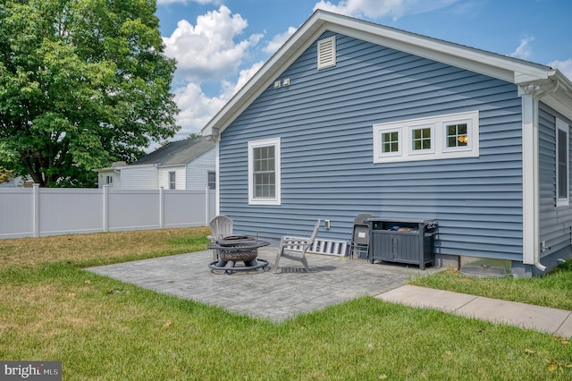 rear view of house featuring a patio area, fence, a lawn, and a fire pit