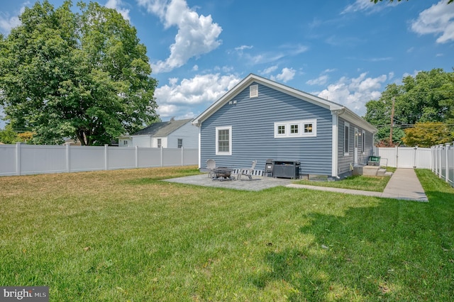 rear view of property with a patio area, a lawn, a fenced backyard, and a fire pit