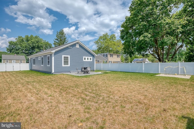 rear view of property featuring a patio, a yard, and a fenced backyard