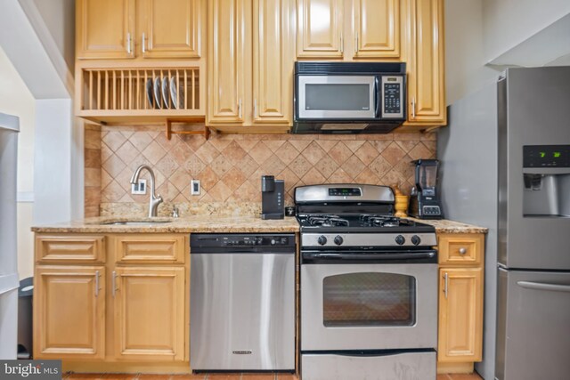 kitchen featuring light stone countertops, sink, stainless steel appliances, and backsplash