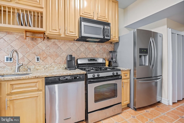 kitchen featuring sink, backsplash, light tile patterned floors, stainless steel appliances, and light stone countertops