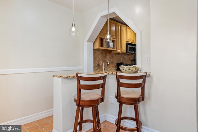 bar with pendant lighting, sink, decorative backsplash, and light stone countertops