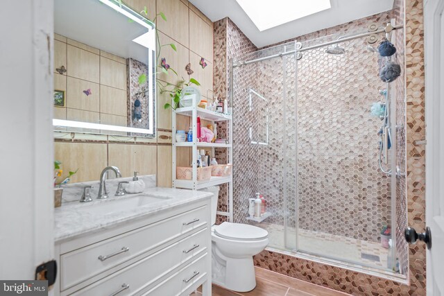 bathroom featuring a skylight, toilet, an enclosed shower, tile patterned flooring, and vanity