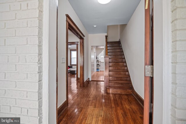 corridor featuring brick wall and dark hardwood / wood-style floors