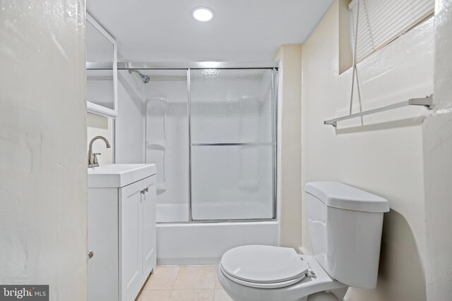 full bathroom featuring toilet, tile patterned floors, vanity, and bath / shower combo with glass door