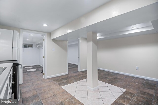 basement with white refrigerator and tile patterned flooring