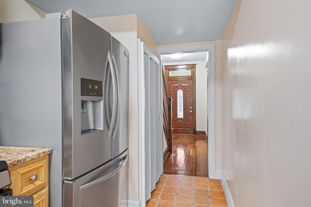 kitchen with stainless steel refrigerator with ice dispenser, light tile patterned flooring, and light stone countertops