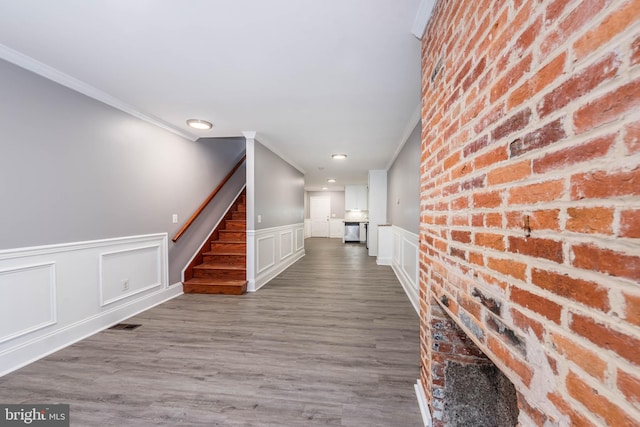 hall featuring brick wall, ornamental molding, and dark hardwood / wood-style floors