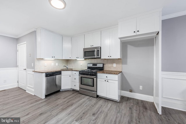 kitchen featuring sink, stainless steel appliances, dark stone counters, and white cabinets