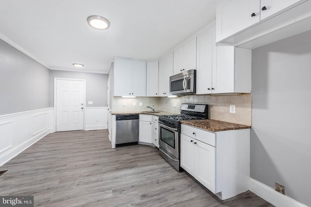 kitchen with dark stone countertops, tasteful backsplash, stainless steel appliances, and white cabinets