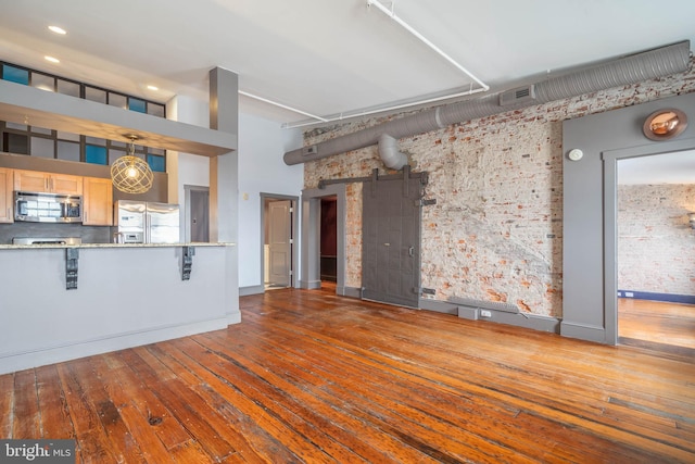 unfurnished living room with hardwood / wood-style flooring, a barn door, and a towering ceiling