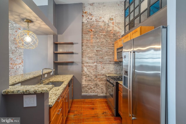 kitchen featuring dark wood-type flooring, a high ceiling, decorative light fixtures, kitchen peninsula, and stainless steel appliances