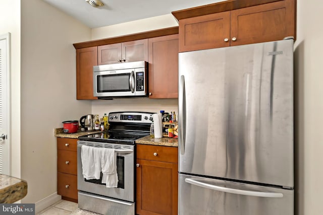 kitchen with stainless steel appliances, light stone counters, and light tile patterned floors