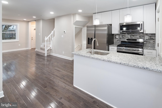 kitchen with backsplash, light stone counters, dark hardwood / wood-style floors, stainless steel appliances, and sink