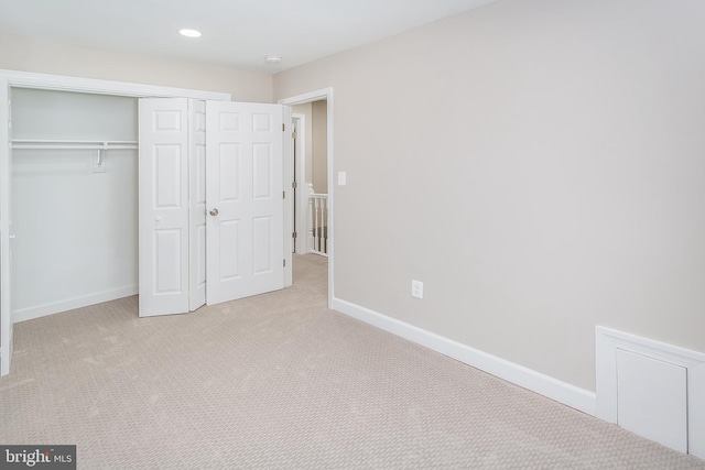 unfurnished bedroom with light colored carpet and a closet