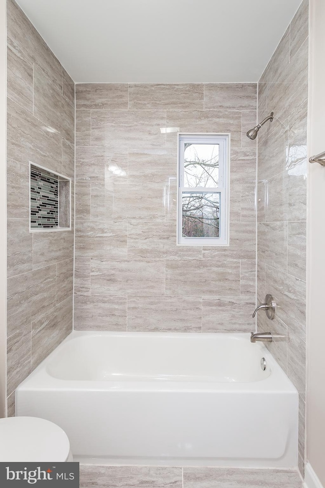 bathroom featuring tiled shower / bath and toilet