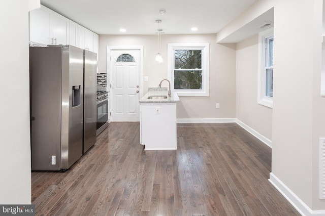 kitchen with sink, appliances with stainless steel finishes, hanging light fixtures, white cabinets, and dark hardwood / wood-style flooring