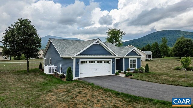 view of front of house featuring a garage, a mountain view, and a front lawn