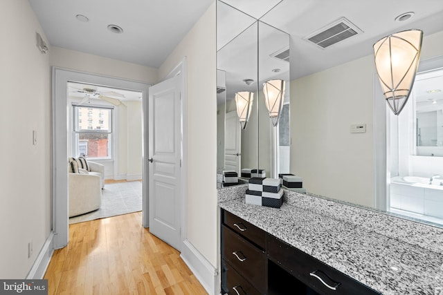 bathroom with ceiling fan, vanity, a bathing tub, and hardwood / wood-style floors