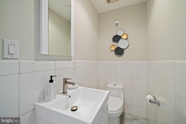 bathroom featuring sink, tile walls, and toilet