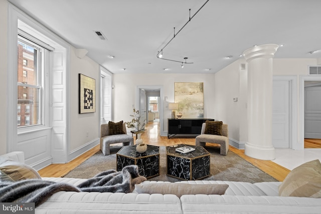 living room featuring ornate columns and light wood-type flooring