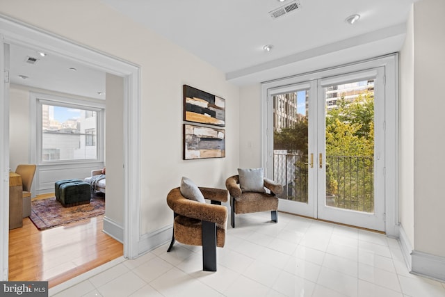 living area featuring french doors, light hardwood / wood-style floors, and a healthy amount of sunlight