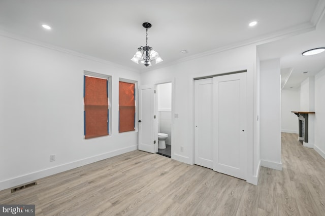 unfurnished bedroom featuring ensuite bathroom, crown molding, a chandelier, a closet, and light hardwood / wood-style floors