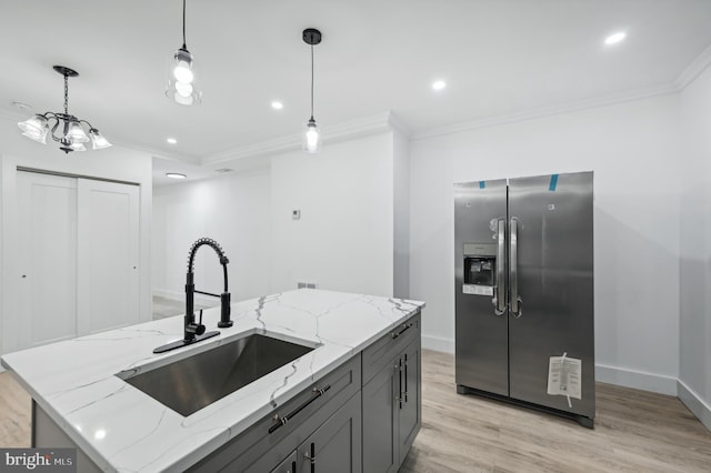 kitchen with an island with sink, light stone countertops, sink, and stainless steel fridge