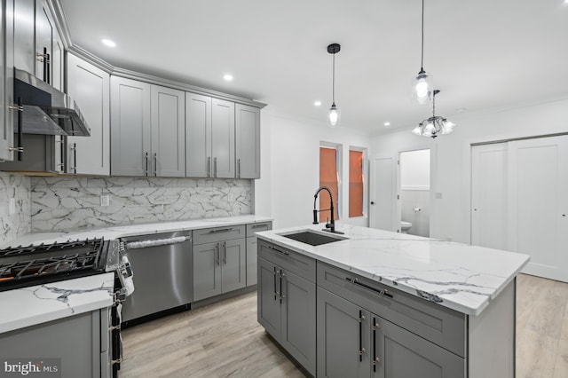 kitchen with gray cabinets, appliances with stainless steel finishes, decorative light fixtures, an island with sink, and sink