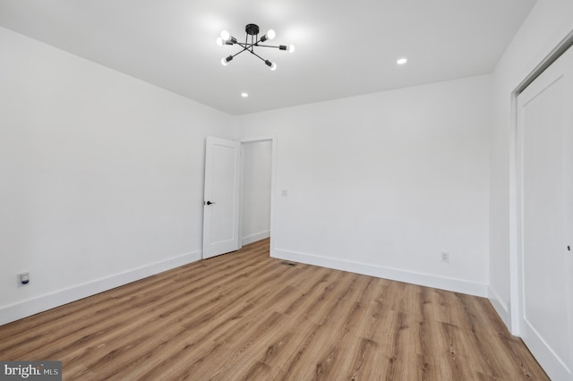 unfurnished bedroom with an inviting chandelier and light wood-type flooring