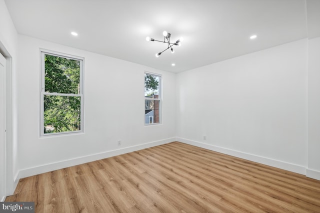 spare room with light hardwood / wood-style flooring and a notable chandelier