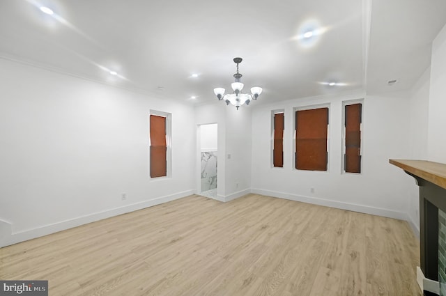 unfurnished living room featuring an inviting chandelier, ornamental molding, and light hardwood / wood-style floors