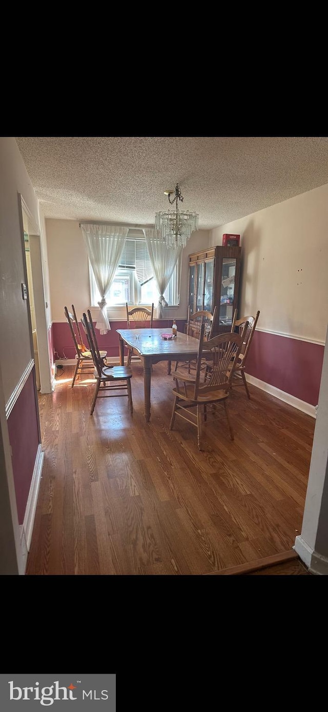 dining area featuring a textured ceiling, a notable chandelier, and wood-type flooring