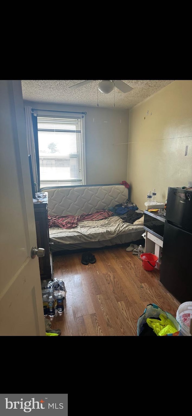 bedroom with a textured ceiling, ceiling fan, wood-type flooring, and vaulted ceiling