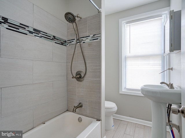 bathroom with tile patterned floors, tiled shower / bath, and toilet