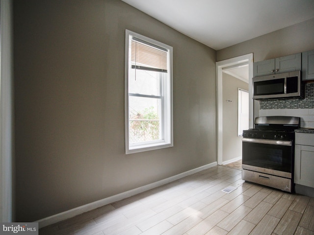 kitchen featuring stainless steel appliances, gray cabinetry, backsplash, and light hardwood / wood-style floors