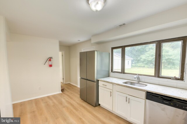 kitchen with sink, white cabinets, light hardwood / wood-style floors, stainless steel appliances, and light stone countertops