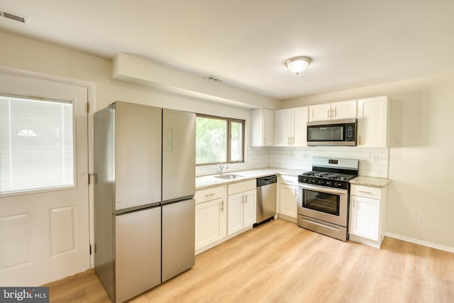 kitchen featuring appliances with stainless steel finishes, sink, light hardwood / wood-style flooring, and white cabinets