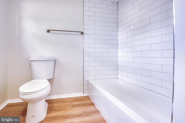 bathroom with tiled shower / bath combo, wood-type flooring, and toilet