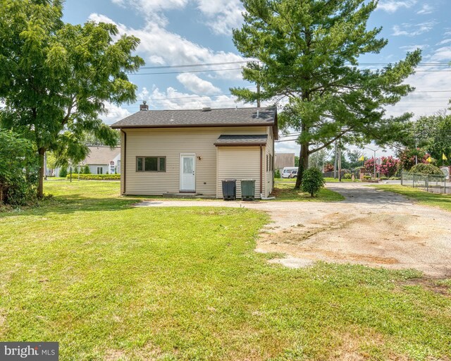 back of property with central air condition unit and a lawn