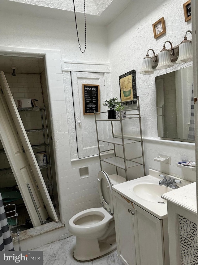 bathroom with vanity, tile patterned flooring, a tile shower, and toilet